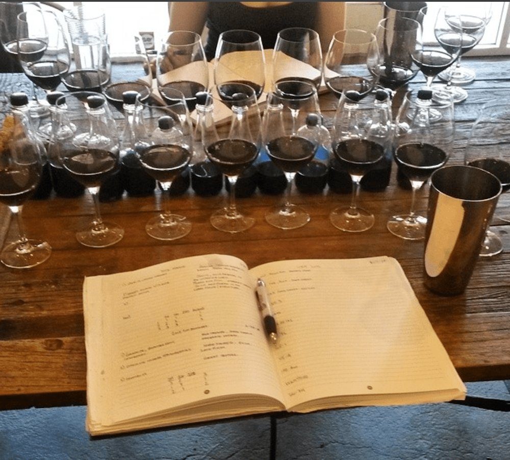 Benchtop blends, wine glasses, and a notebook are used for blind blending trials